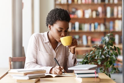 hardworking-female-student-with-heap-of-books-drink